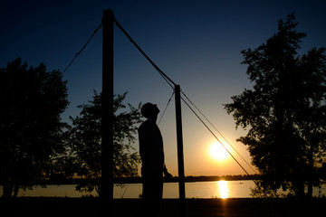 Fototapeta na wymiar young man doing pull ups on horizontal bar outdoors during sunset - fitness, sport, exercising, training and lifestyle concept