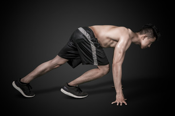 Shirtless young man ready to run in the dark room