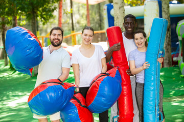 Portrait of happy friends with inflatable logs and pillows at an amusement park