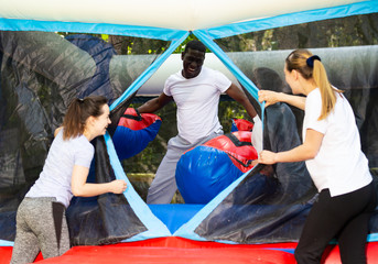 Gambling friends boxing giant gloves on an inflatable trampoline in an amusement park