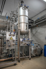 Large steel reservoir or tanks and metal pipes in modern juice and water production plant. Industrial background