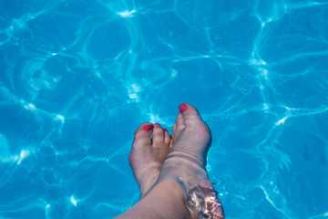 woman's feet splashing in the pool