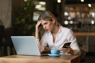 Frustrated businesswoman reading a problematic e-mail on a computer in a cafe