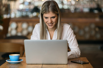 Beautiful businesswoman  typing an e-mail on laptop in a cafe