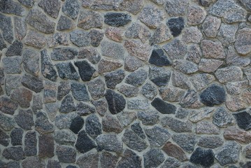 gray stone texture of large cobblestones in the wall of the fence