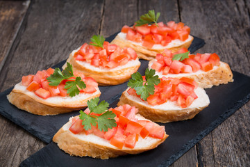 Traditional Italian bruschettas with cherry tomatoes on stone plate