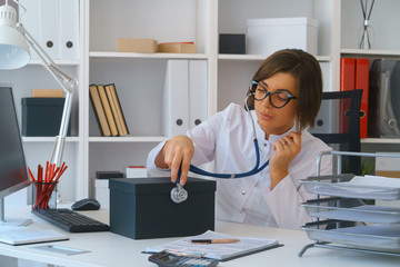 young beautiful doctor in white gown stay in her consulting room wait for patients