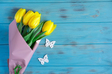 Photo with tulips on a wooden background with butterflies. Frame for greeting card with flowers. Background for a banner with flowers. Flat lay, top view.