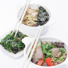 Isolated chinese food on a white background. Food is placed in the pot. Nearby lie chopsticks.