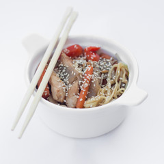 Isolated chinese food on a white background. Food is placed in the pot. Nearby lie chopsticks.