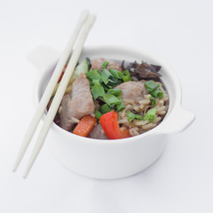 Isolated chinese food on a white background. Food is placed in the pot. Nearby lie chopsticks.