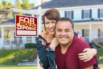 Mixed Race Young Adult Couple In Front of House and Sold For Sale Real Estate Sign