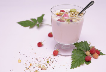 yogurt with granola and ripe raspberries in a glass and raspberries with leaves on a white background with copy space for text. Milk products. Healthy food 