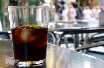 Glass of cola with ice at outdoor restaurant and bar