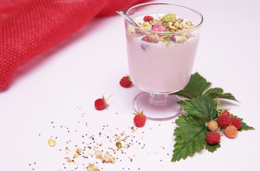 yogurt with granola, chia and ripe raspberries in a glass and raspberries with leaves on a white and red background with copy space for text. Healthy food 