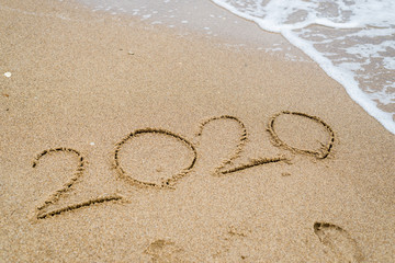2020 written on the seashore of the ocean sea on the sand.