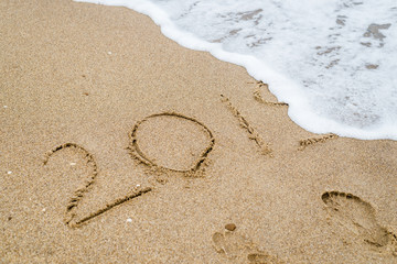 2019 inscription on sand washed away by the wave of the sea, ocean.