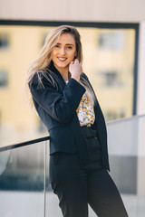 a stylish woman in a black suit looks at the camera and leans ag