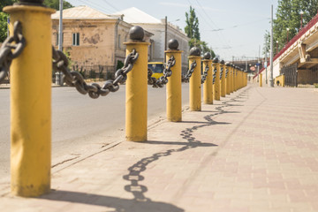 Fencing thick chain on yellow pillars along the road.