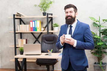 Start day with coffee. Coffee relaxing break. Boss enjoying energy drink. Caffeine addicted. Man bearded businessman hold cup stand office. Successful people drink coffee. Coffee is always good idea