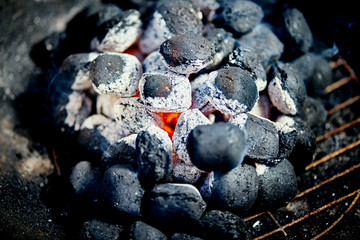 Closeup of glowing coal in metal grill on summer day in garden