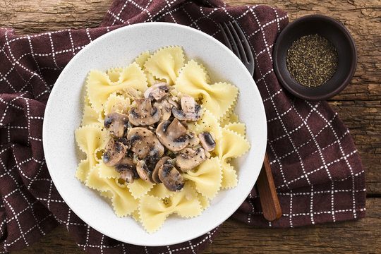 Fresh Homemade Creamy Vegetarian Mushroom Sauce On Farfalle Pasta Served In Bowl, Ground Black Pepper On The Side, Photographed Overhead (Selective Focus, Focus On The Dish)