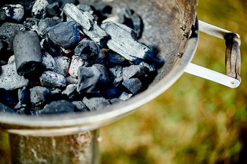 Closeup of glowing coal in metal grill on summer day in garden
