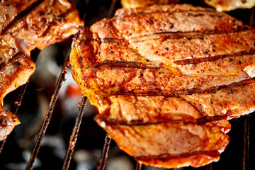 Juicy beef steaks on grill with flame on barbecue in the garden