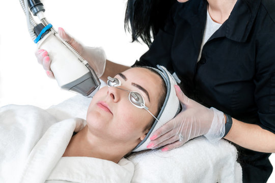 Young woman undergoing a laser skin treatment for non-ablative skin resurfacing to remove wrinkles, acne scars and other facial impurities at a medical spa.
