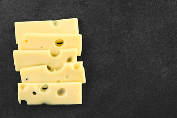 Slices of Emmental, Emmentaler or Emmenthal cheese on slate, photographed overhead with copy space...