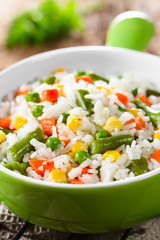 Cooked white rice mixed with colorful vegetables (onion, carrot, green peas, corn, green beans) in bowl (Selective Focus, Focus one third into the dish)