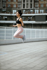 Fit brunette woman training with jump rope at the sports ground