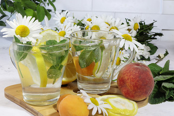 Herbal tea with mint, chamomile and lemon on a sunny table. Summer drinks made from natural herbs are very useful and charge with energy and good mood