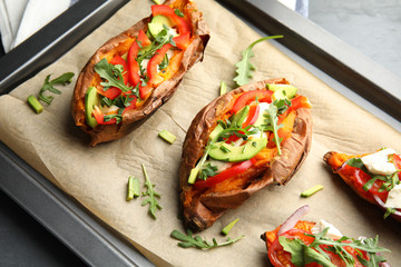 Baking sheet with stuffed sweet potatoes on table, closeup