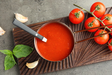 Flat lay composition with pan of sauce and tomatoes on grey table