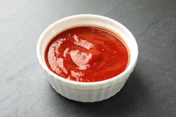 Bowl of tasty tomato sauce on grey table