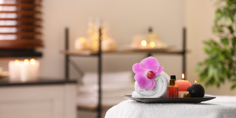 Composition with towel, candles and oils on massage table in spa salon. Space for text