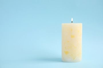 Alight wax candle on color background. Space for text