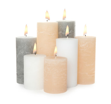 Many alight wax candles on white background