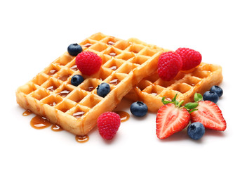 Yummy waffles with berries and caramel syrup on white background