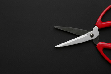 Pair of sharp scissors on dark background, top view. Space for text