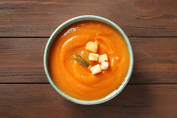 Bowl of tasty sweet potato soup on wooden background, top view