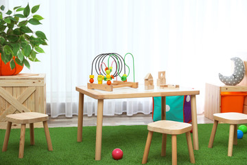 Stylish playroom interior with toys and modern wooden furniture