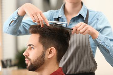 Barber making stylish haircut with professional scissors in beauty salon