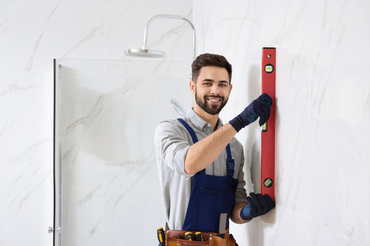 Handyman working with building level in bathroom. Professional construction tools