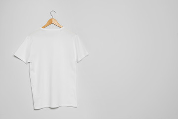 Hanger with blank t-shirt on gray background. Mock up for design