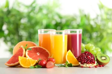 Poster Im Rahmen Drei Gläser mit verschiedenen Säften und frischen Früchten auf dem Tisch vor unscharfem Hintergrund © New Africa
