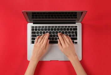 Fototapeta na wymiar Woman using modern laptop at color table, top view