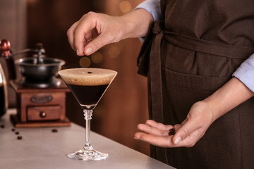 Woman preparing Espresso Martini on bar counter, closeup. Alcohol cocktail