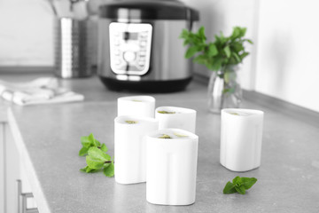 Containers with delicious fresh yogurt made in modern multi cooker on table